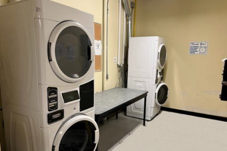 Two stacked washers and dryers with a large table between for folding or sorting