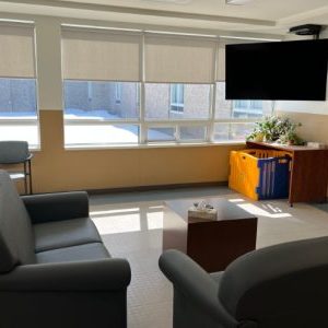 Common room with bright sunny windows, couches, and a tv