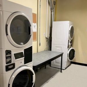 Two stacked washers and dryers with a large table between for folding or sorting