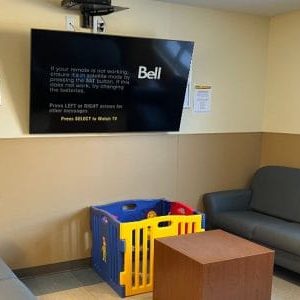 A large TV mounted on the wall. Kids play area is below with a couch on either side